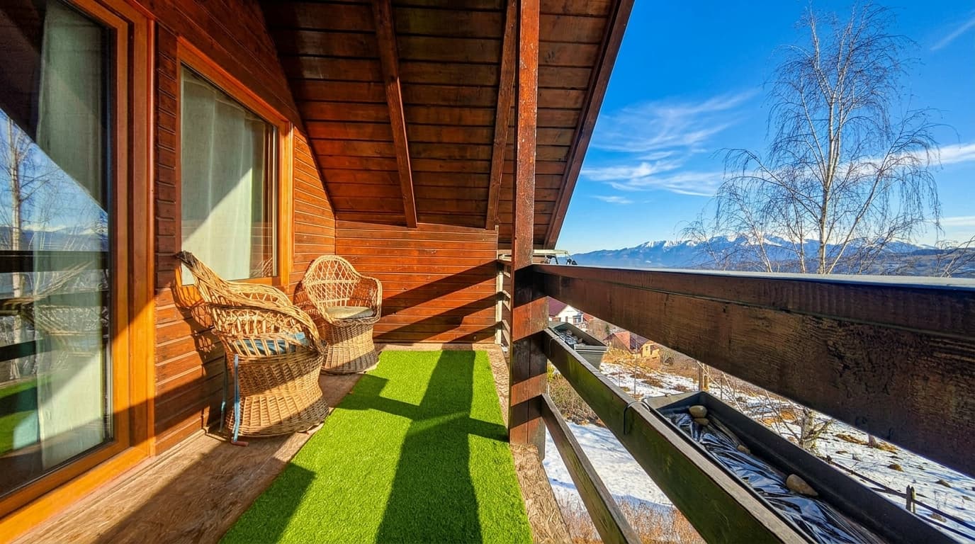 Balcon cu fotolii de răchită și priveliște spre munți